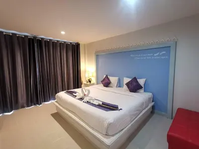 a bedroom with a large white bed with a large window at Phuket Racha Kata Homestay in Kata Beach
