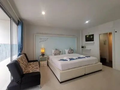 a bedroom with a large bed and a chair at Phuket Racha Kata Homestay in Kata Beach