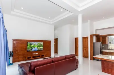 a living room with a brown leather couch and a flat screen tv at Villa Bang Tao 3 Bedroom Q Kata Residence in Bang Tao Beach