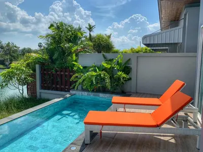 a patio with orange chairs and a swimming pool at Villa Bang Tao 3 Bedroom Q Kata Residence in Bang Tao Beach