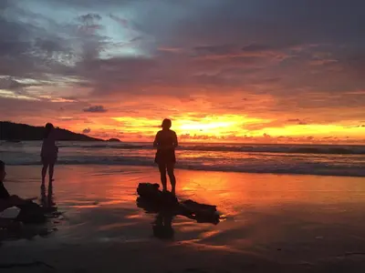 a group of people standing on the beach at sunset at Freedom Hotel in Patong Beach