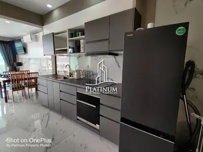 a kitchen with white cabinets and a black refrigerator at Villa Versace Residence in Patong Beach