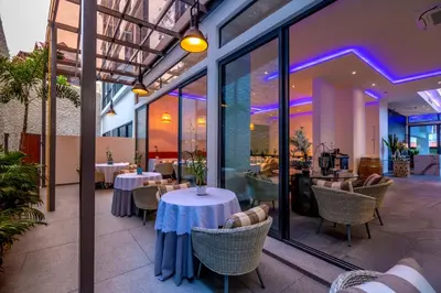 a restaurant with white tables and chairs and windows at Patong Heights in Patong Beach