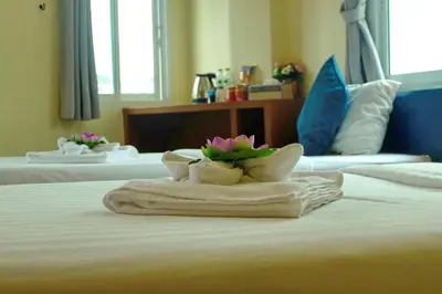 a hotel room with two towels with flowers on a bed at Calypso Patong Hotel in Patong Beach