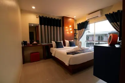 a bedroom with a bed and a large window at Calypso Patong Hotel in Patong Beach