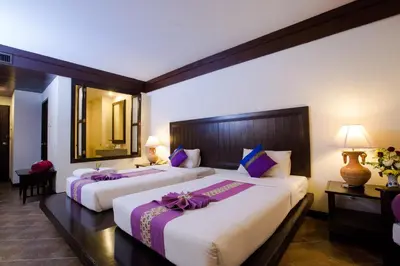 a hotel room with two beds with purple bows on them at Kata Poolside Resort SHA Extra Plus in Kata Beach