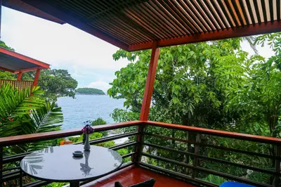 a balcony with a table and a view of the water at Mom Tri's Villa Royale - SHA Plus in Kata Beach