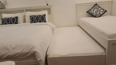 two beds in a small room with white sheets and pillows at Wora Stay room Kata beach in Kata Beach