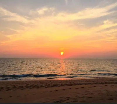 a sunset on the beach with the sun setting at Baan mai khao apartment in Mai Khao Beach