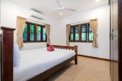 a bedroom with a bed in a room with windows at Thai Style 2BR Villa Nikkie 2 in Nai Harn Beach