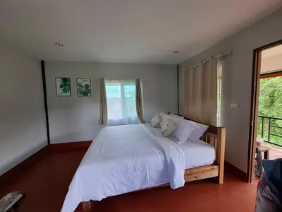 a bedroom with a bed with white sheets and a window at The Best Bungalow in Ban Bang Chak