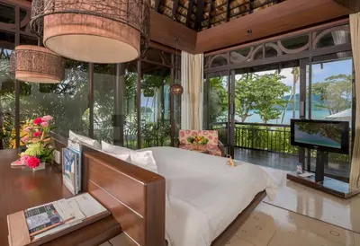 a bedroom with a bed and a tv and windows at The Vijitt Resort Phuket - SHA Extra Plus in Rawai Beach