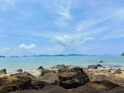 a beach with rocks and the ocean on a cloudy day at Sunrise Beach Kohyao Resort in Ko Yao Yai