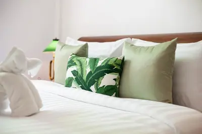 a white teddy bear sitting on a bed with pillows at Sound Gallery House - SHA Plus in Phuket Town
