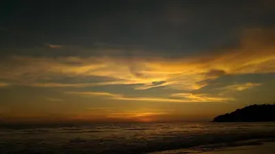 a sunset on the beach with the sun setting at Ramada by Wyndham Phuket Southsea in Karon Beach