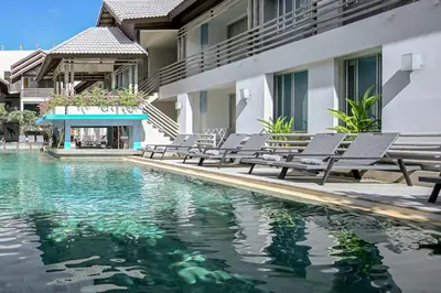 a swimming pool with chaise lounge chairs next to a building at Ramada by Wyndham Phuket Southsea in Karon Beach