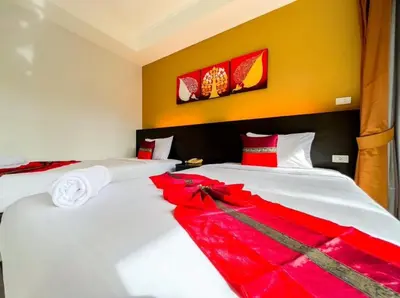 two beds in a hotel room with red decorations at Naiyang Beach Hotel SHA Plus in Nai Yang Beach