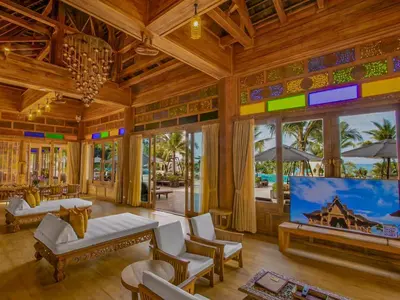 a living room with wooden ceilings and a large screen tv at Santhiya Phuket Natai Resort & Spa in Natai Beach