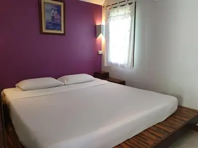 a large white bed in a purple room with a window at P.P. Casita - Adult Only in Phi Phi Don