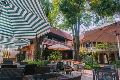 an outdoor patio with tables and chairs with umbrellas at Garden Home Kata in Kata Beach