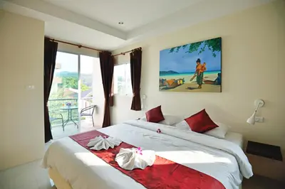 a bedroom with a large white bed with red pillows at At Kamala Hotel in Kamala Beach