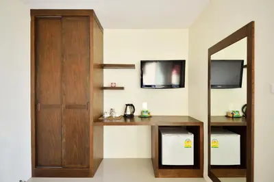 a room with a desk and a mirror and a tv at At Kamala Hotel in Kamala Beach
