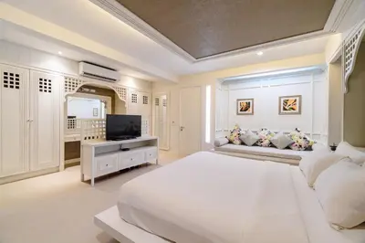 a white bedroom with a large bed and a television at Villa Pimmada in Ao Nang Beach