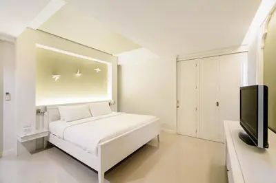 a white bedroom with a bed and a flat screen tv at Villa Pimmada in Ao Nang Beach