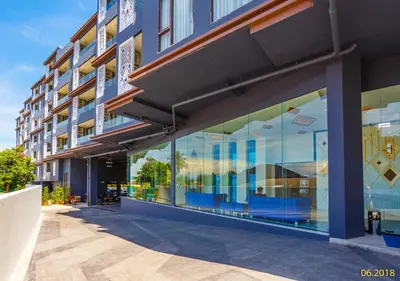 a building with large glass windows on a street at The Aristo Beach by Holy Cow, studio, construction view in Surin Beach