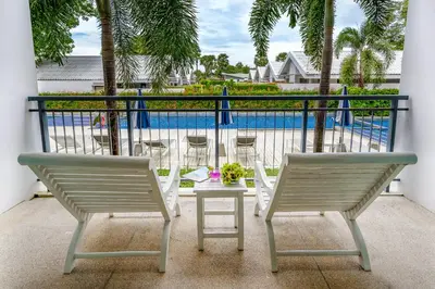 two chairs and a table on a balcony with a pool at The Palmery Resort in Kata Beach