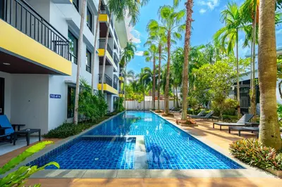 a swimming pool in the middle of a building with palm trees at Anchan Boutique Hotel in Chalong