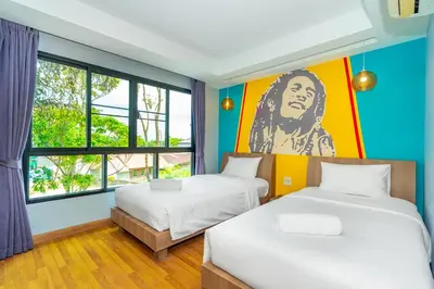 a room with two beds and a painting of a man at Anchan Boutique Hotel in Chalong