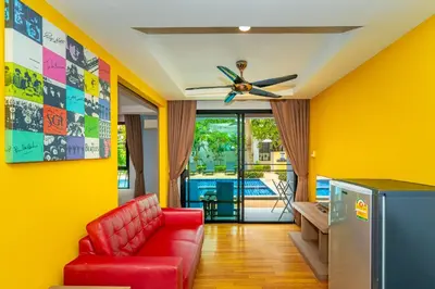 a living room with a red couch and a ceiling fan at Anchan Boutique Hotel in Chalong