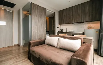 a living room with a couch and a kitchen at Rak Elegant Hotel Patong in Patong Beach