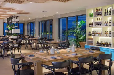 a restaurant with tables and chairs and windows at Cape Sienna Phuket Gourmet Hotel & Villas - SHA Extra Plus in Kamala Beach