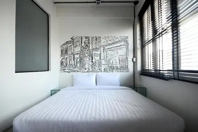 a bed in a room with a drawing on the wall at Quip Bed & Breakfast in Phuket Town