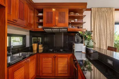 a kitchen with wooden cabinets and a sink at VILLA TOGIAN Private Pool Naiharn beach in Rawai Beach