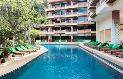 a swimming pool with chairs and a building at Baumanburi Hotel Patong in Patong Beach