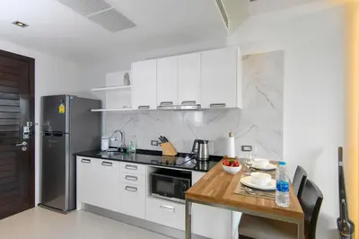 a kitchen with white cabinets and a wooden table at Emerald Terrace Resort in Patong Beach