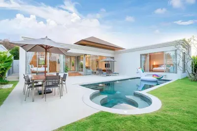 a villa with a pool and a table and chairs at Trichada Tropical in Bang Tao Beach
