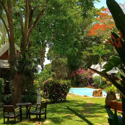 a garden with a table and chairs and a swimming pool at Le Passe-Temps in Tha Lane Bay