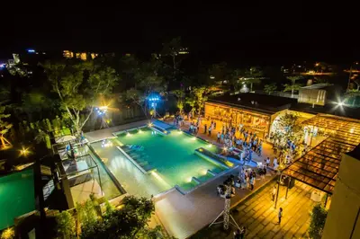 a group of people standing around a swimming pool at night at The Gallery Hotel Nai Harn in Nai Harn Beach