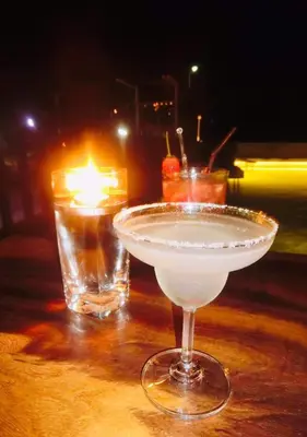 a drink in a glass on a table with a candle at The Gallery Hotel Nai Harn in Nai Harn Beach