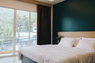 a bedroom with a large bed and a large window at Tall Tree Kata Phuket in Kata Beach