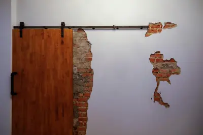 a wall with a wooden door and a brick wall at Tall Tree Kata Phuket in Kata Beach