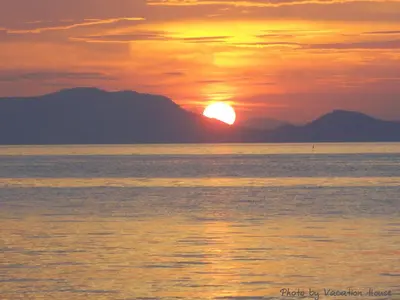 a sunset over the water with mountains in the background at Vacation House in Klong Muang Beach