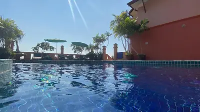 a swimming pool in front of a building with palm trees at Baan Kongdee Sunset Resort Kata in Kata Beach