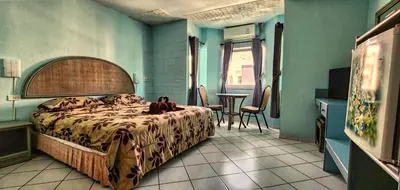 a bedroom with a bed and a table in a room at Pension Zum Ross in Karon Beach