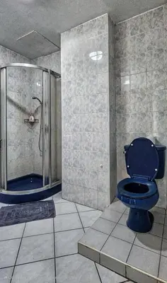 a bathroom with a blue toilet and a shower at Pension Zum Ross in Karon Beach