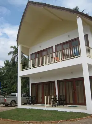 a white building with a balcony and tables and a truck at Naga Peak Resort in Ao Nang Beach